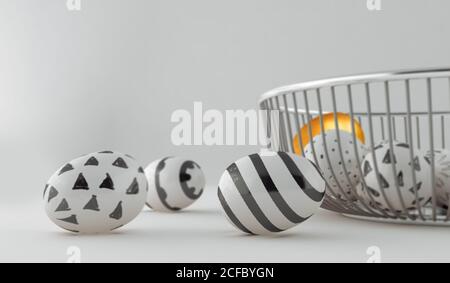 Painted decorated easter eggs on wire basket next to a golden egg on white background Stock Photo