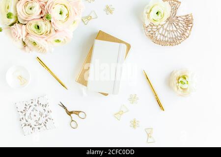 Workspace with diary, gold accessories, ranunculus flowers on white background. Home office desk. Top view feminine background. Flat lay, top view. Stock Photo
