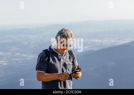 Senior man using his mobile phone on the mountain Stock Photo