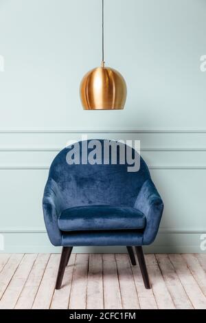 Blue armchair on turquoise background with a golden lamp Stock Photo