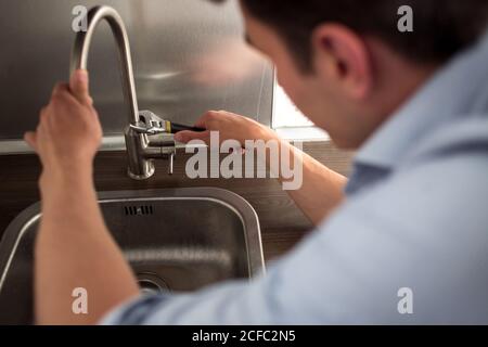 Male Plumber In Overall Fixing Sink Pipe. Stock Photo