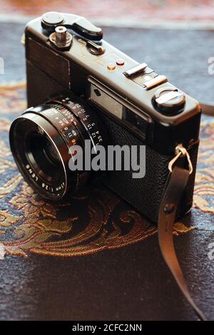 Closeup of retro photo camera placed on textured embroidered fabric Stock Photo