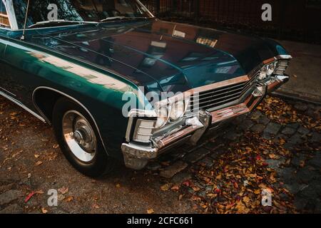 Retro car of dark blue color with shiny chrome bumper parked on cobblestone street in fallen leaves, New York Stock Photo