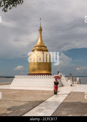 Woman with traditional umbrella walking next to Buddhist pagoda Stock Photo