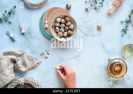 Zero waste Easter background on marble table. Quail Easter eggs and natural Spring decorations, eucalyptus twigs. Green tea in glass teapot. Hand with Stock Photo