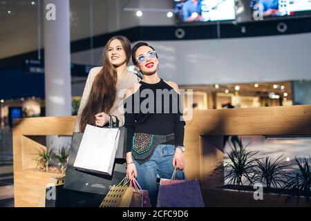 Portrait of two cheerful caucasian girls shopping in mall Stock Photo