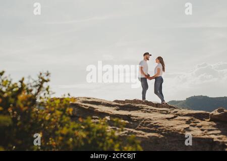 Loving couple holding hands while standing at mountain cliff Stock Photo