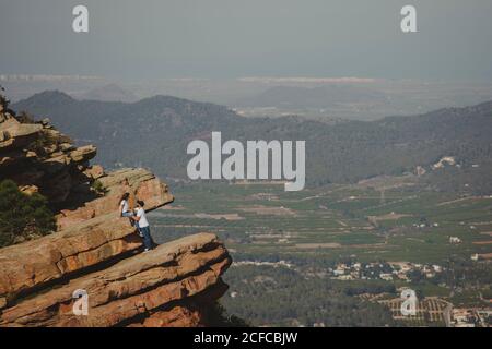 Distant loving couple standing on high cliff Stock Photo