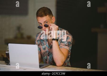 Focused young man working on laptop at table throughout a windows in coffee shop Stock Photo