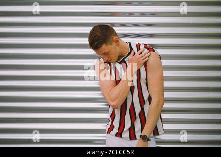 Handsome happy man leaning on steel garage door looking down Stock Photo