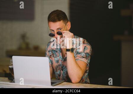 Focused young man working on laptop at table throughout a windows in coffee shop Stock Photo