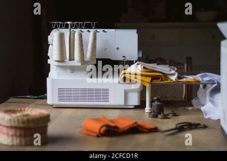 Modern workplace of dressmaker with sewing machine and cloth and threads on wooden table at home Stock Photo
