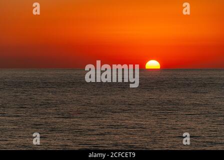 Cabo San Lucas, Mexico - November 23, 2008: Red sky sunset of half-sunk sun into dark Pacific Ocean in the evening. Stock Photo