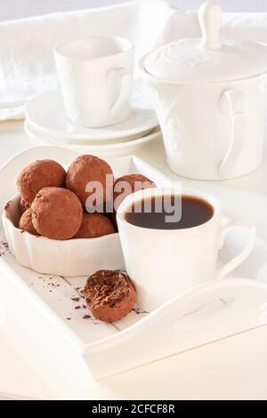 Homemade vegan chocolate truffles cocoa powder white plate morning light. Healthy tasty diet sweets concept. Stock Photo