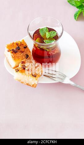 Basbousa (namoora) traditional arabic semolina cake with almond nut and syrup and glass of maroccan mint tea. Copy space. Selective focus. Pink backgr Stock Photo