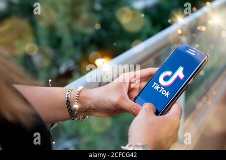 Young Woman with smartphone in her hands and TIK TOK logo on the screen. Stock Photo