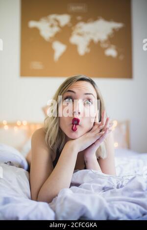 Young attractive Woman making funny faces while lying in bed in morning Stock Photo