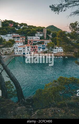 Sailboats on sea water against houses on rocky shore Stock Photo