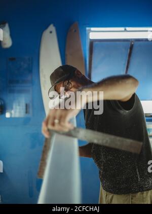 Carpenter diligently making surfboard in workshop Stock Photo