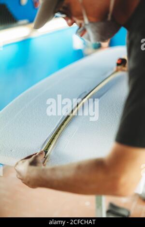 Workman with measuring tape making surf board Stock Photo