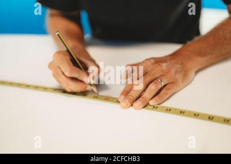 Workman with measuring tape making surf board Stock Photo
