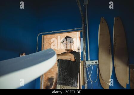 Carpenter diligently making surfboard in workshop Stock Photo