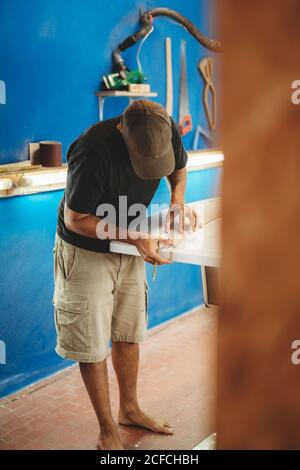 Workman with measuring tape making surf board Stock Photo
