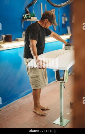 Workman with measuring tape making surf board Stock Photo