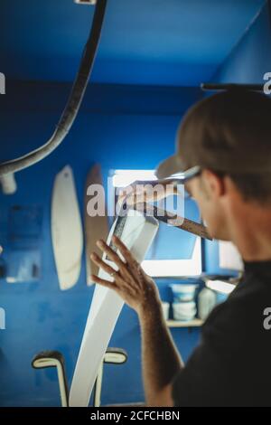Carpenter diligently making surfboard in workshop Stock Photo