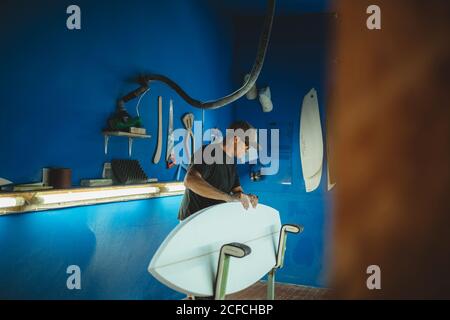 Carpenter diligently making surfboard in workshop Stock Photo