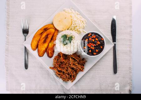 Homemade Venezuelan food. Traditional Venezuelan dish. Pabellon Criollo. White Rice, Black beans, Fried plantains, and Shredded beef Stock Photo