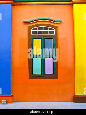 Colourful wooden shutters on a restored building with bright orange walls and yellow and blue columns. Stock Photo