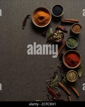 Top view composition with different kinds of natural aromatic spices placed on dark gray background Stock Photo