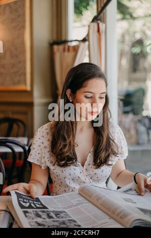 young pretty lady reading a newspaper in a vintage coffee shop Stock Photo