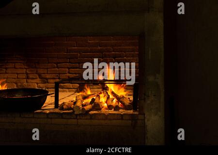 Orange flames of fire and black skillet on brick fireplace indoors Stock Photo