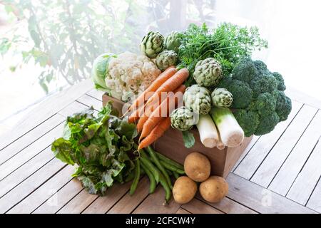 From above of harvest of various ripe vegetables placed in wooden box in garden Stock Photo