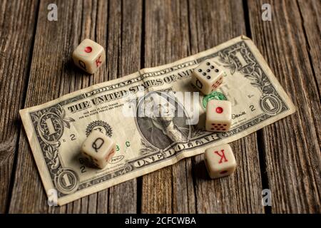 From above of white dice six sided dots set for playing with box on dollar bill on wooden table Stock Photo