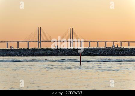 Lateral view of the Øresund Bridge in the evening light, walkers on the pier in the foreground Stock Photo