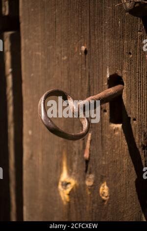 Large old key in the keyhole, close-up, dark wooden door