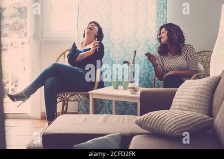 Couple of caucasian firends or women in relationship at home having fun and laughing a lot with happiness - lockdown and coronavirus stayhome concept Stock Photo