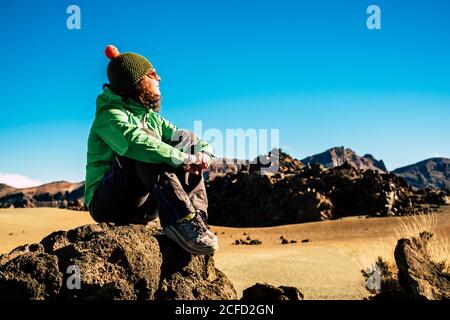 Adult caucasian woman in healthy trekking outdoor sport and leisure activity - young female sit down on the rocks and enjoy and rest in a mountain Stock Photo