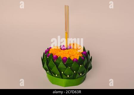 Banana leaf Krathong that have 3 incense sticks and candle decorates with flowers for Thailand full moon or Loy Krathong festival on pink background. Stock Photo
