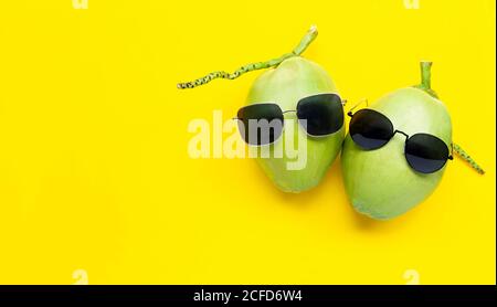 Two young oconut with sunglasses on yellow background.  Enjoy summer holiday concept. Top view Stock Photo