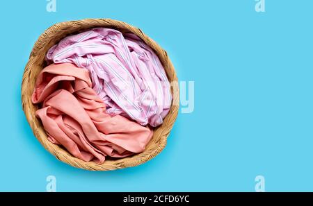 Colorful clothes in laundry basket on blue background. Copy space Stock Photo