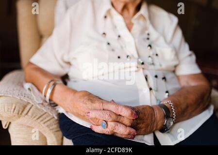 Portrait of happy senior curly gray haired Woman in white shirt and with beads on neck looking at camera at home Stock Photo