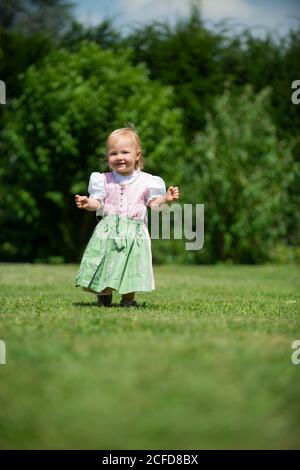 Girl in Dirndl runs across a meadow, Upper Bavaria, Bavaria, Germany Stock Photo