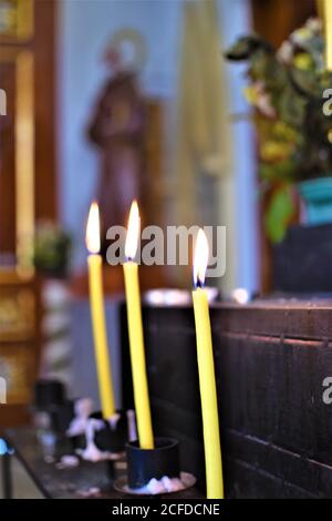 Lighted yellow candles on a prayer altar inside a church Stock Photo