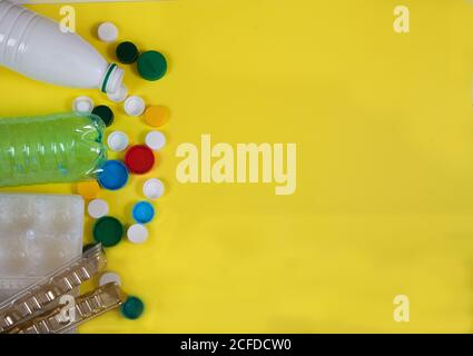Waste, garbage from plastic bottles, cups, lids on a yellow background. Zero waste. Stock Photo