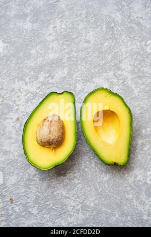 Top view of fresh ripe avocado cut in half on light grey texture background Stock Photo
