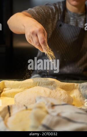 From above of faceless female hands kneading bunch of fresh dough at table in bakery Stock Photo